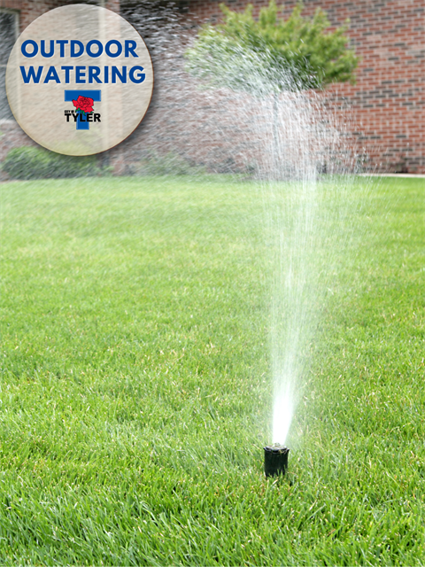 An in-ground sprinkler spraying water over a green lawn, with a circular overlay in the top-left corner labeled 